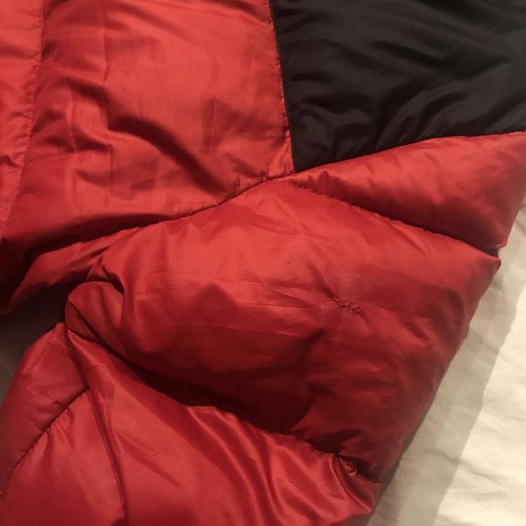 The North Face Photos displaying two small sewed up patches on Red NorthFace 700 XL Puffer product image