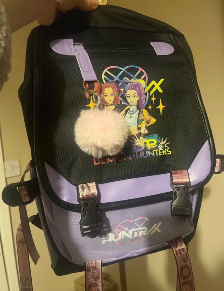 Black And Purple Backpack With Cartoon Graphic And Pompom Keychain